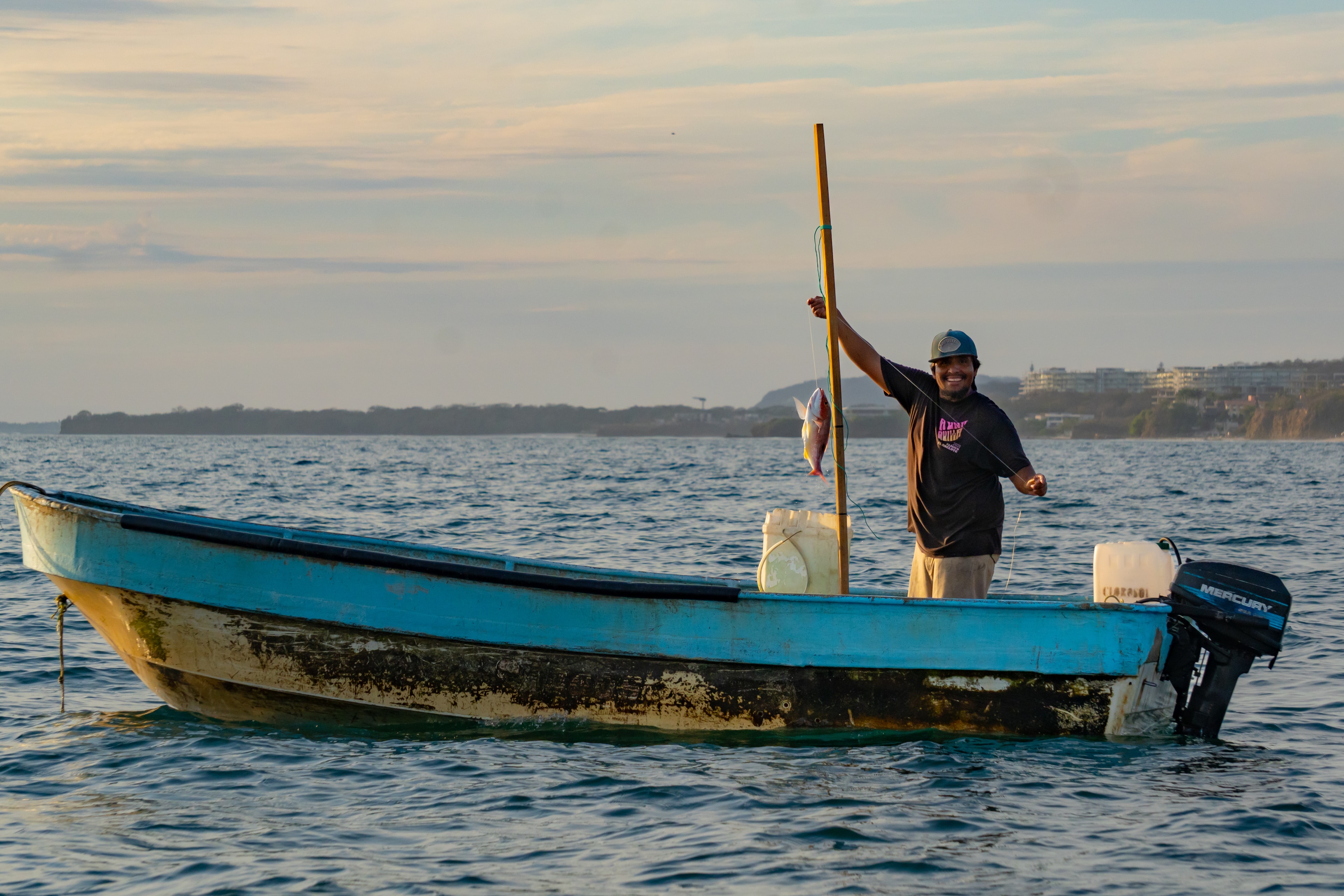 Pescador sosteniendo su captura en barco azul